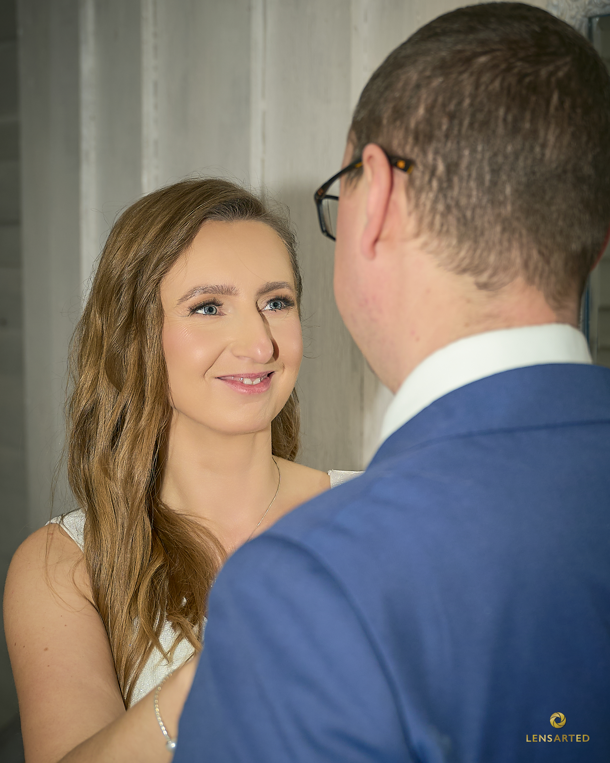 Para młoda w intymnym momencie — panna młoda z uśmiechem patrzy na pana młodego.